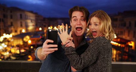 Newly engaged couple taking a selfie by the Grand Canal at night