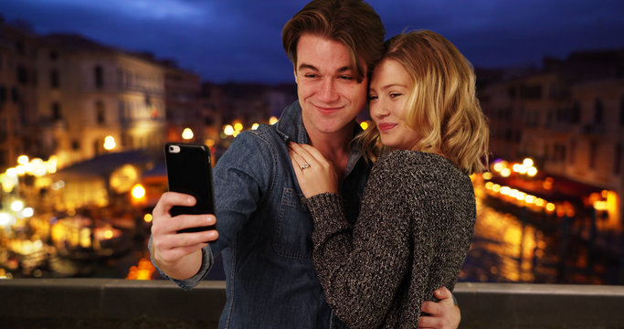 Newly engaged couple taking a selfie by the Grand Canal at night