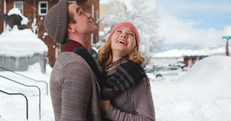 Happy Caucasian couple enjoying winter day in the snow smiling and laughing