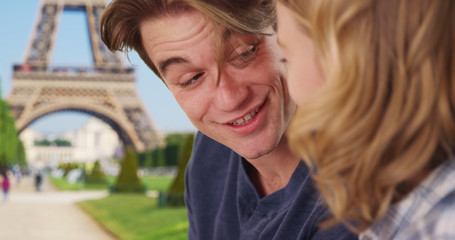 Cheerful man and woman relax by the Eiffel Tower chatting