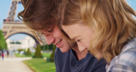 Side view of cheerful couple in Paris chatting and using technology
