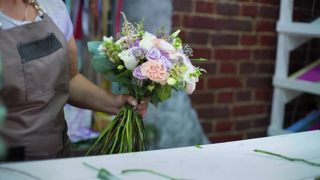 professional florist arranging wedding bouquet in floral design studio. Caucasian female master in apron creating flower bunch composition. Floristry, handmade and small business concept