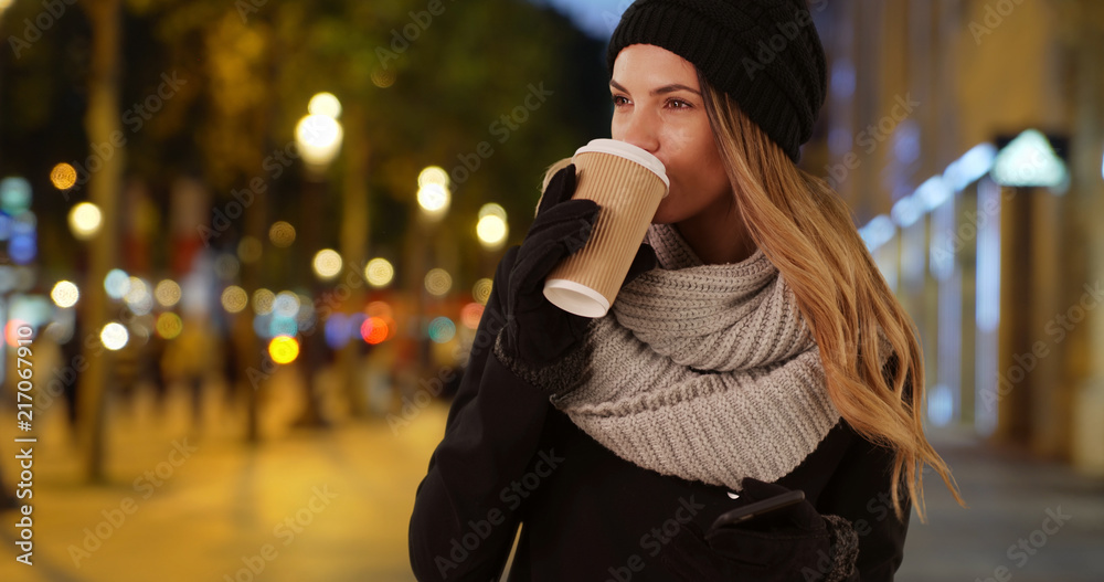 Wall mural Attractive woman drinking her coffee in urban setting at night - Wall murals
