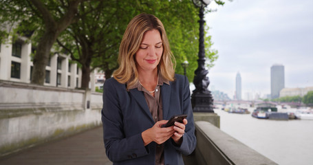 Portrait of Caucasian businesswoman texting on smart phone outside London