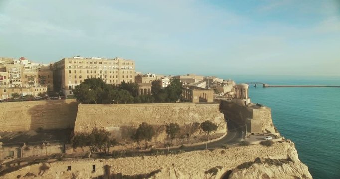 Aerial Shot over City between blue skies and blue sea