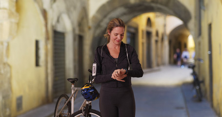Obraz na płótnie Canvas Woman in Florence resting from bike ride using fitness tracker