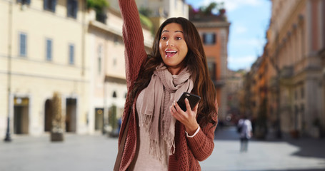 Fototapeta premium Pretty Latina woman with her phone smiling and saying hi