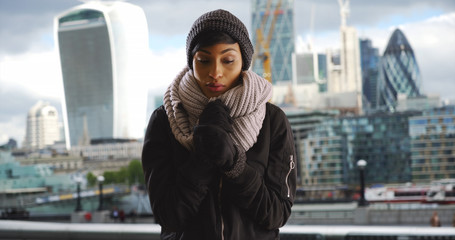 Attractive black woman wearing cozy hat and scarf on overcast day in the city