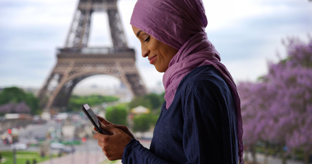 Young beautiful Muslim woman in Paris France texting near the Eiffel Tower