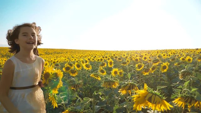 Happy little girl running happy free across the field with sunflowers. slow motion video . smelling big sunflower on summer field. Delight of a pleasant smell. Summer holiday. concept happiness girl