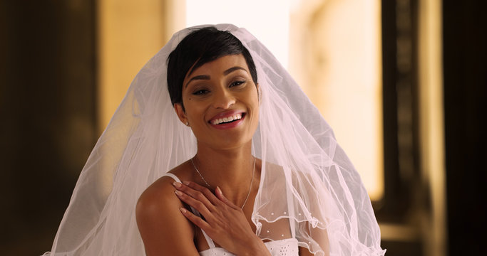 Happy beautiful bride lifts away her veil laughing and excited