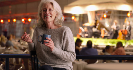 Attractive older woman in cafe listening to band playing on stage snaps fingers