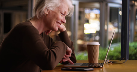 Happy older woman browsing internet in coffee shop with wifi