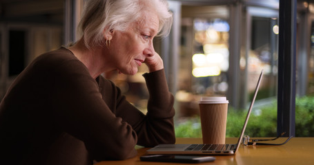 Happy older woman browsing internet in coffee shop with wifi