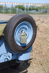 Roda suplente de jipe antigo com cantil de água preso no centro - Willys Jeep restaurado - de cor...