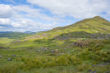 Scenic panorama of green mountains below a blue cloudy sky in summer