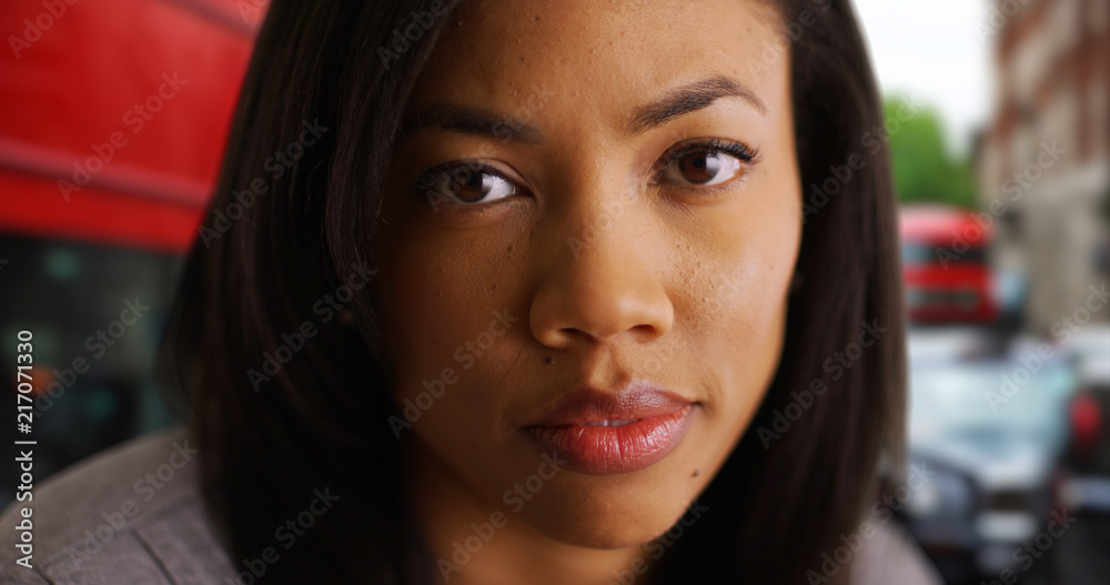 Wall mural Beautiful African American female on urban street in London with somber expression