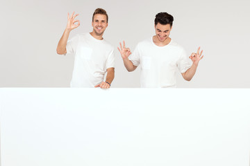 Two guys posing with white empty board.