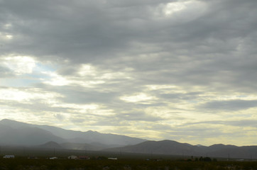 Fototapeta na wymiar monsoon rain clouds over mountain range edging dry Mojave Desert valley landscape in Nevada, USA