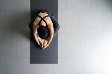 Young woman practicing yoga in  gray background.Young people do yoga indoor.Top view of beautiful young fitness woman working out .