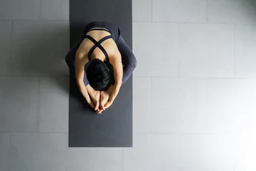 Foto op Plexiglas Young woman practicing yoga in  gray background.Young people do yoga indoor.Top view of beautiful young fitness woman working out . © anon