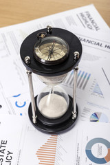 sand timer with compass on the financial paper