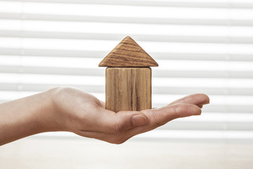 woman hand hold a wood house at the office.