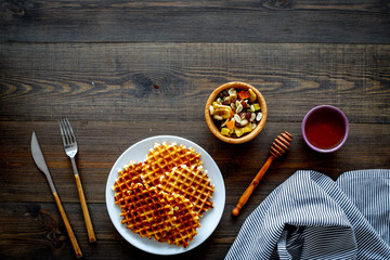 Traditional belgian waffles with dried fruit, nuts and caramel on dark wooden background flat lay copy space