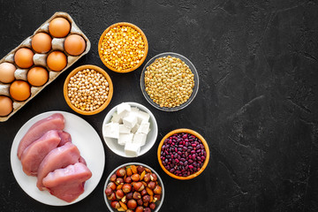 Food for sportsmen. Legumes, nuts, low-fat cheese, meet, eggs on black background top view copy space