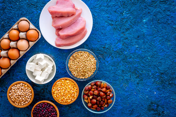 Food for sportsmen. Legumes, nuts, low-fat cheese, meet, eggs on blue background top view copy space