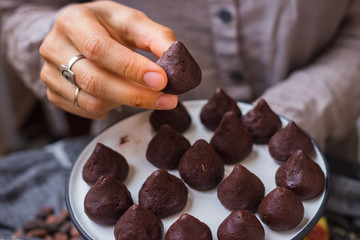 Woman hands holds chocolate truffle confectionary made with grated chocolate, cocoa or carob...