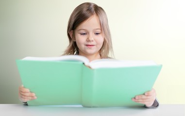 Adorable young girl reading a book