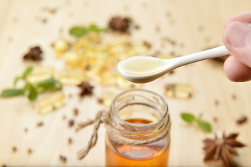 Pouring of fish oil from spoon into bottle on brown wooden background with  many fish oils.