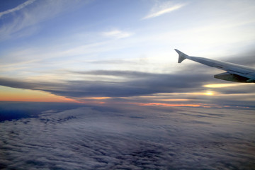 Fototapeta premium High Altitude Sunset over the Clouds from a Plane Window.