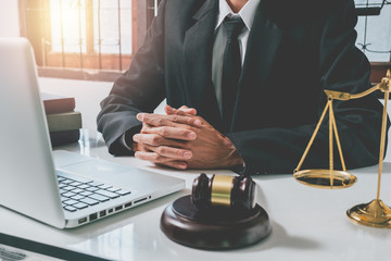 justice and law concept.Male lawyer in the office with brass scale and gavel and laptop and legal book on white wooden table. - obrazy, fototapety, plakaty