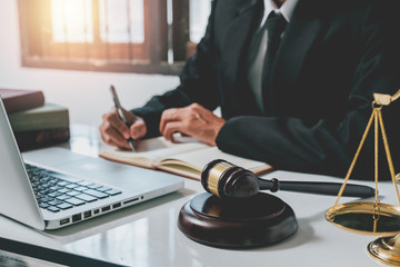 Close up gavel on white desk with Male judge writing notebook background.justice and law concept.