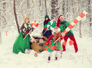 family in traditional Christmas flower costumes, red - green , Santa's helpers - elves, in the...