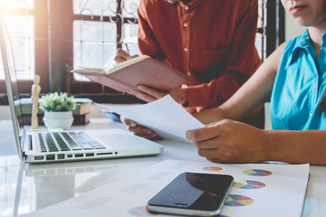Two colleagues discussing data with document data and new modern computer laptop on desk table. Close up business team analysis and strategy concept.
