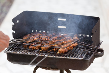 Skewer chicken pieces grilling on the barbecue and smoke.