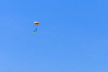 Parachutist carrying flag of Ukraine in blue clear sky