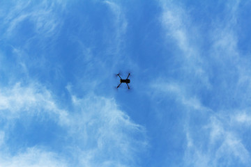 Naklejka na ściany i meble Drone flying overhead in cloudy blue sky