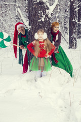 family in traditional Christmas flower costumes, red - green , Santa's helpers - elves, in the winter forest with a chest of gifts and a huge candy