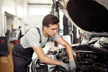 Fototapeta na wymiar A qualified automachanic is repairing a car at a car service