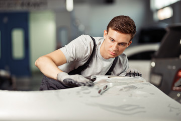 A young blond automechanic is repairing a car at his work