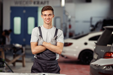 An attractive blond automechanic is smiling during a short break at a car service