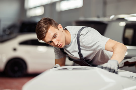 A young mechanic is focused on fixing a white sport car
