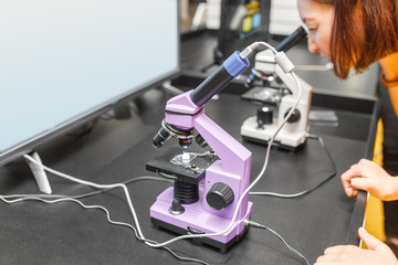 woman scientist looking at the microscope at educational exhibition or museum