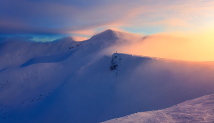 High in the mountains the sun is rising and enlightens everything with wonderful orange color. The mountains are in snow. Unbelievable winter landscape.