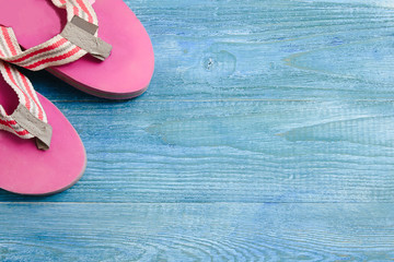 Pink slippers on a blue wooden background, summer background and holiday concept