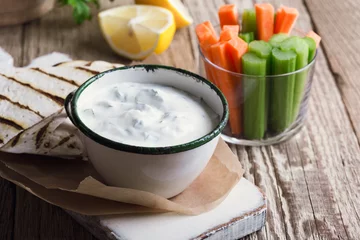 Fototapeten Yogurt dip with parsley  served  with tortilla chips, carrot, and celery sticks © istetiana